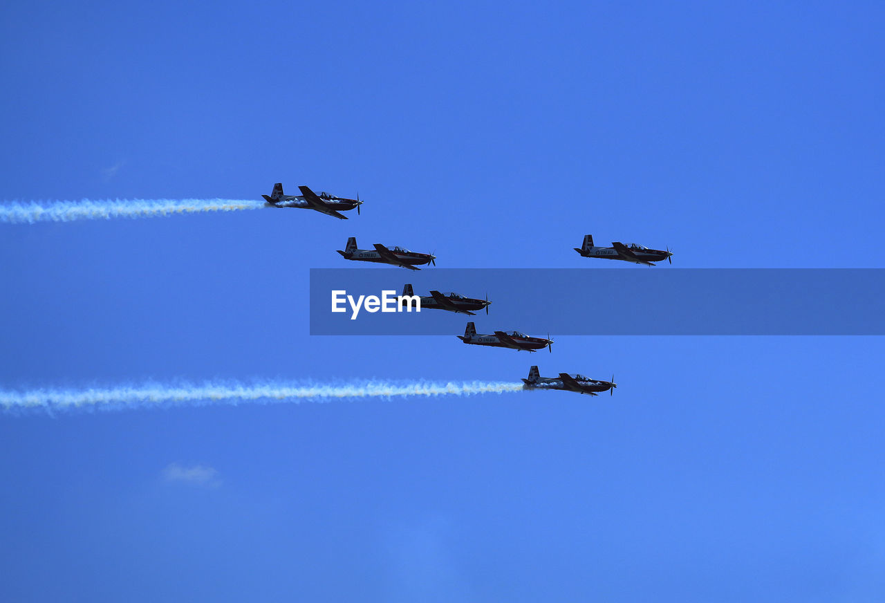 Low angle view of airplanes flying against sky