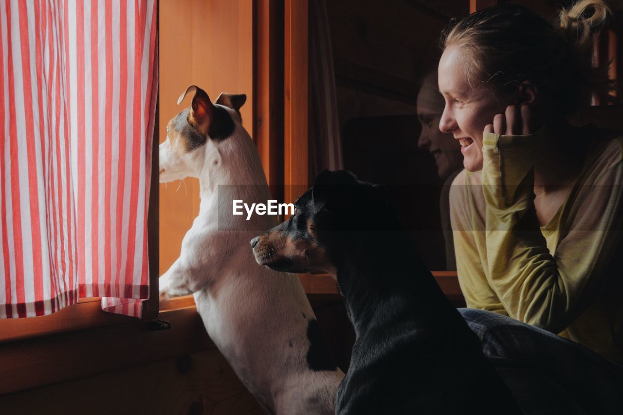 Rear view of woman sitting at home with dogs