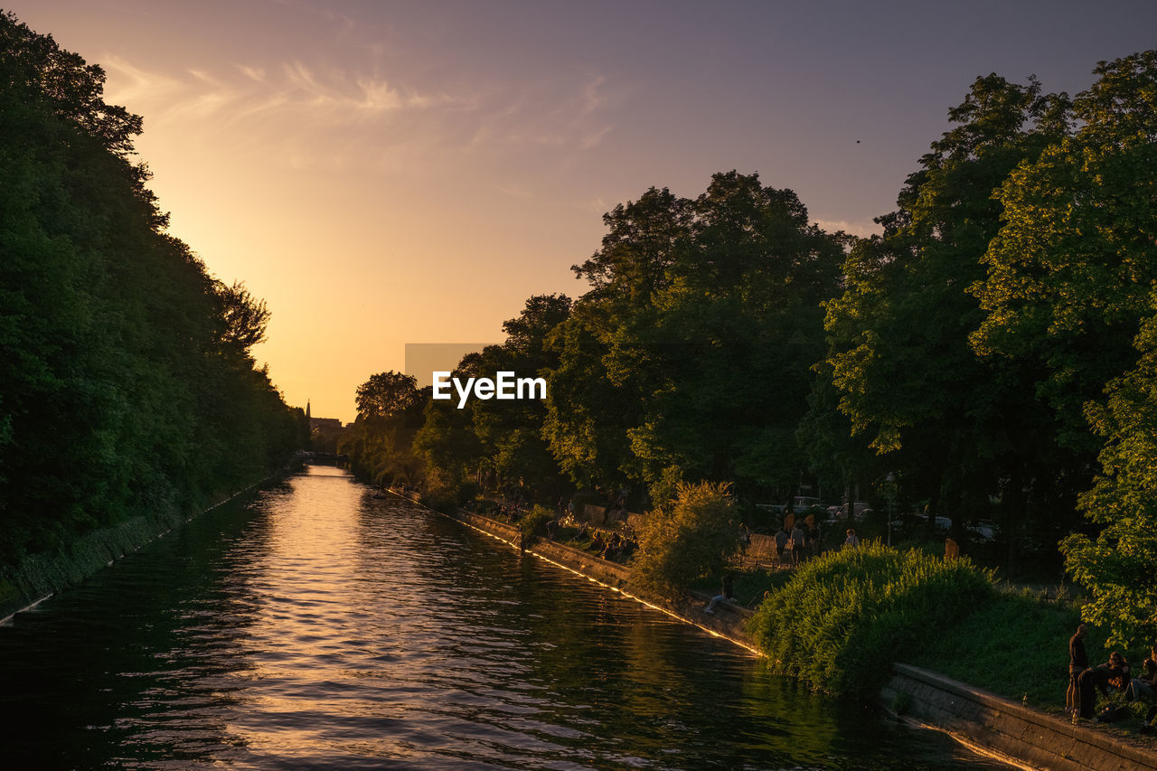 River amidst trees against sky during sunset