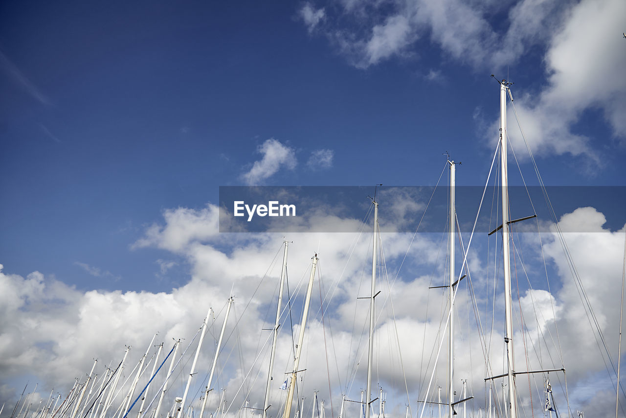 Sailing masts in the harbor of scheveningen with clouds