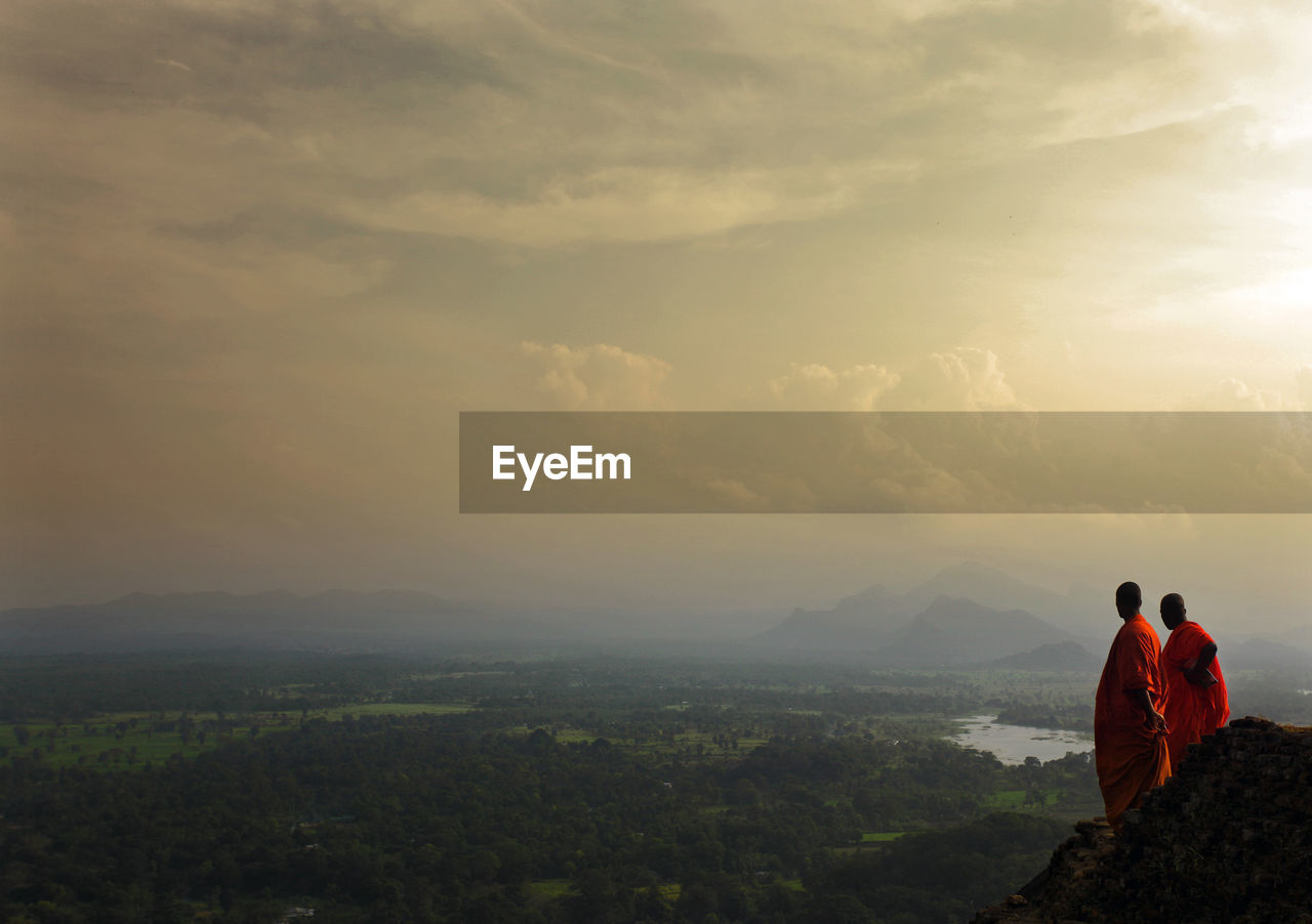 Monk standing on mountain against sky