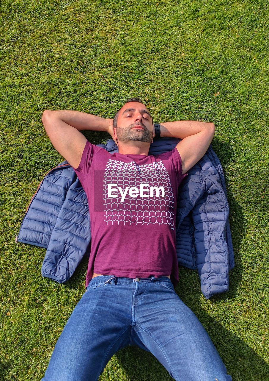 High angle view of man sleeping on grassy field