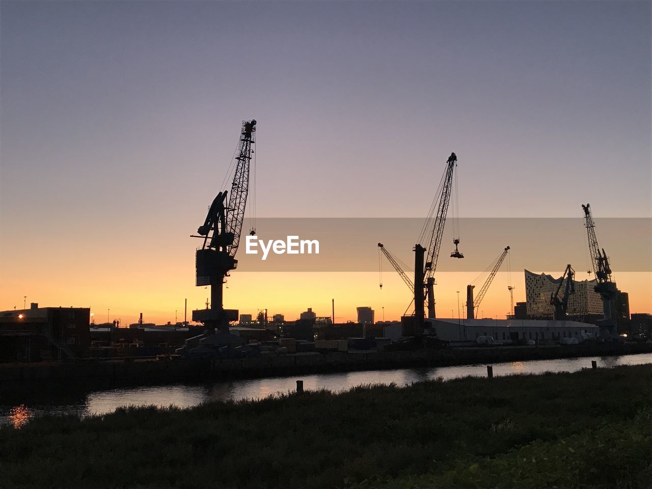 SILHOUETTE CRANES AGAINST SKY AT SUNSET