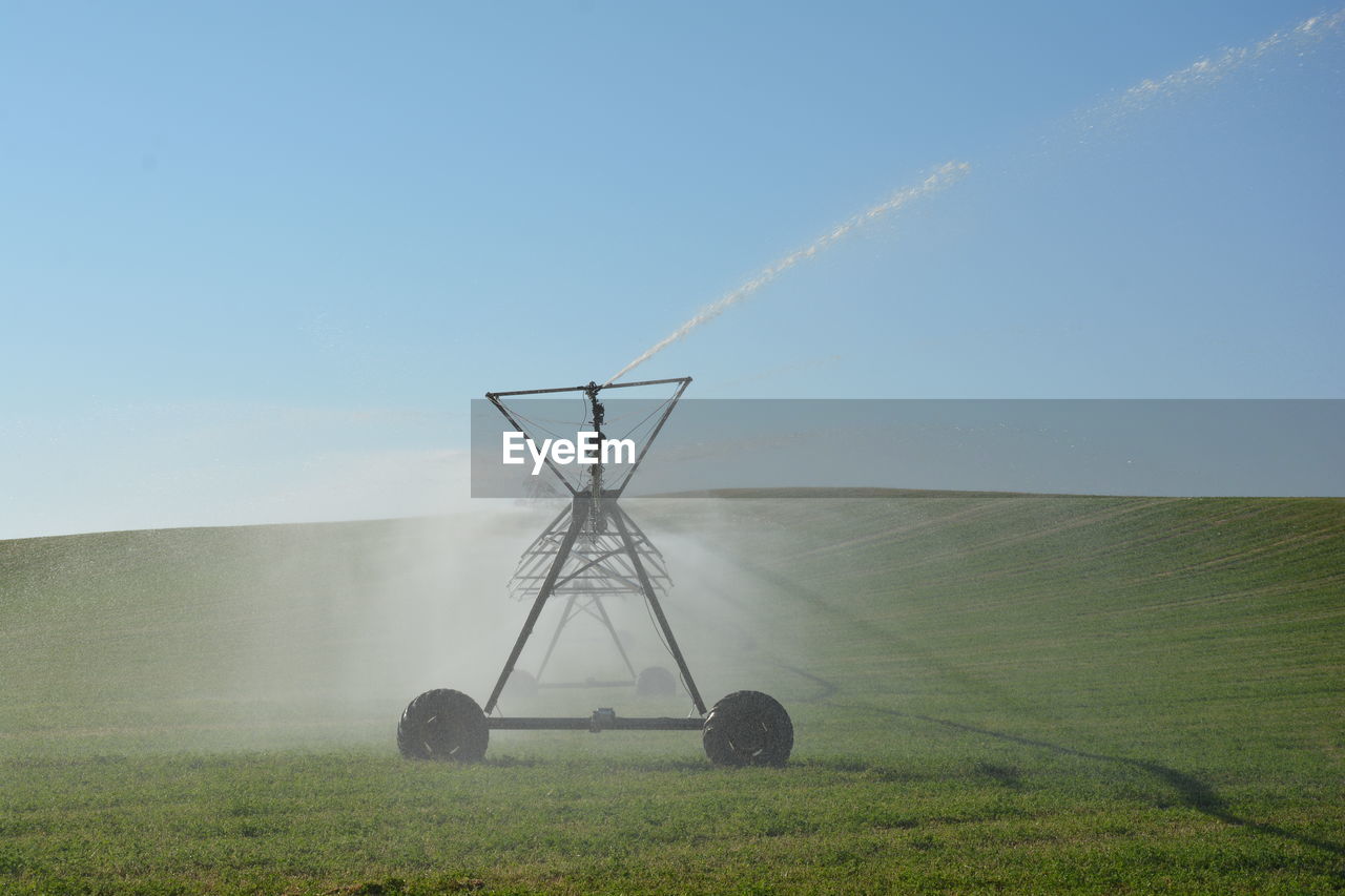 Sprinkler on field against clear sky