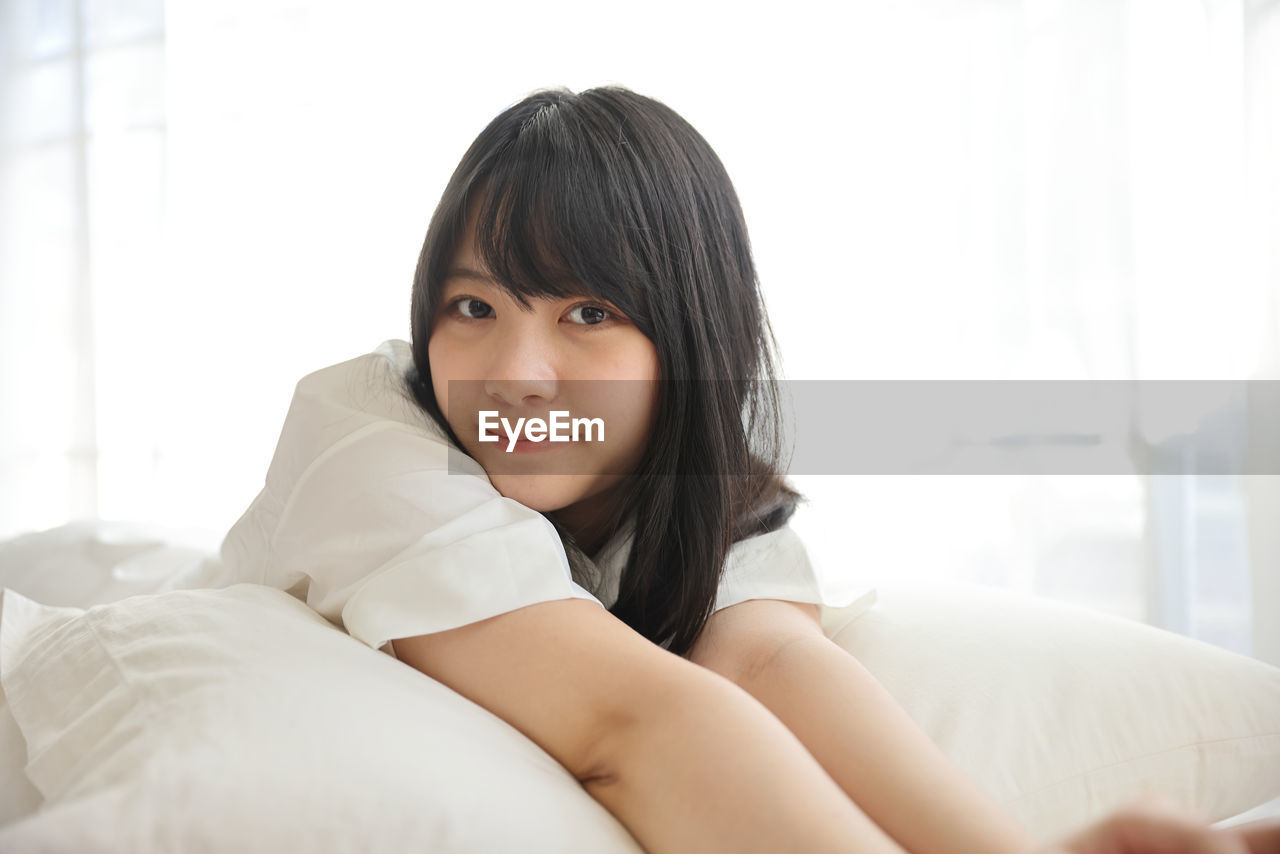 portrait of young woman lying on bed at home