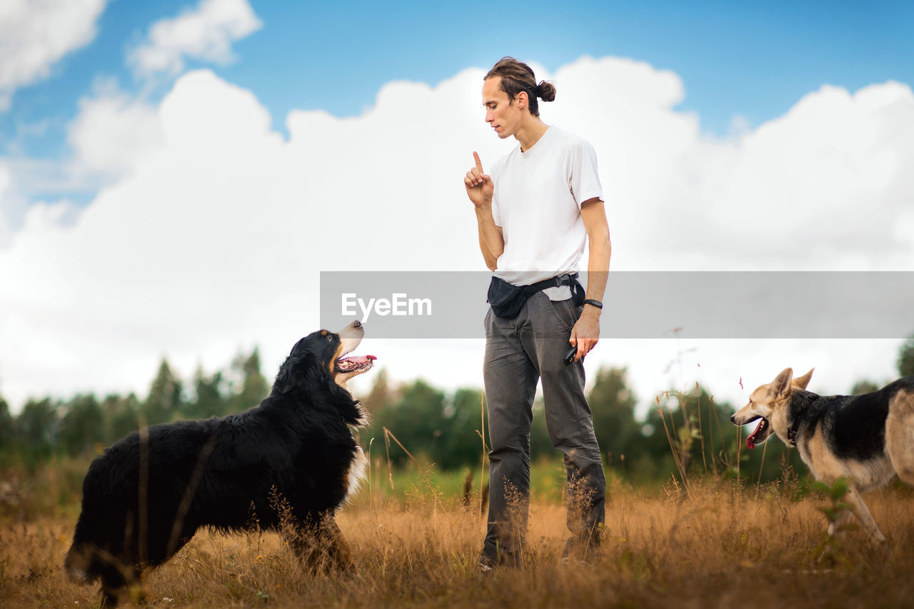 Man playing with dog while standing on land against sky