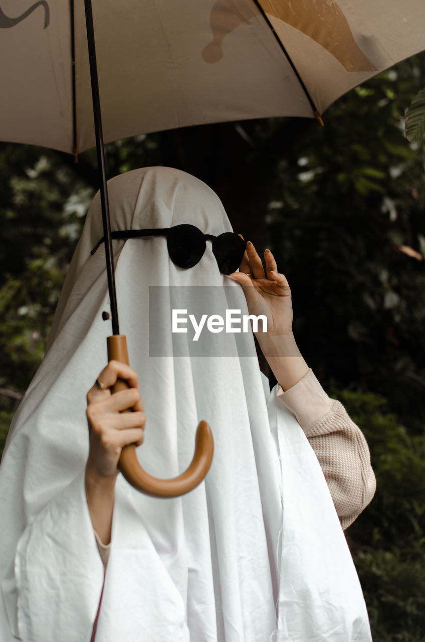 Midsection of person holding white umbrella