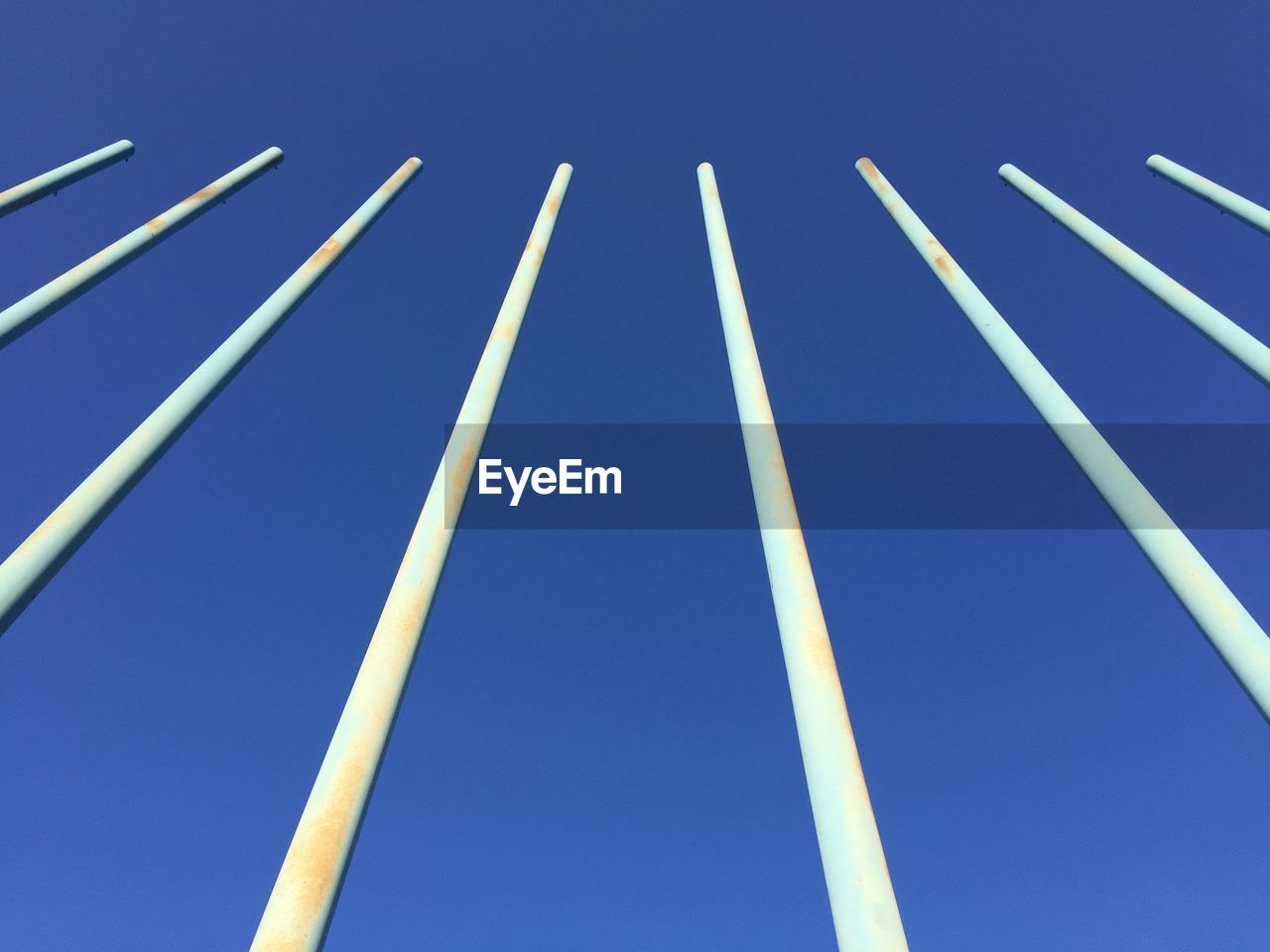 LOW ANGLE VIEW OF POLES AGAINST BLUE SKY