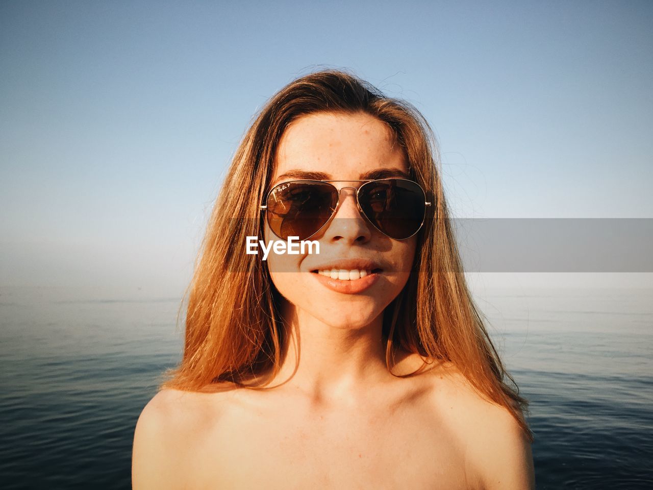 Portrait of sensuous young model in black swimwear standing against sea