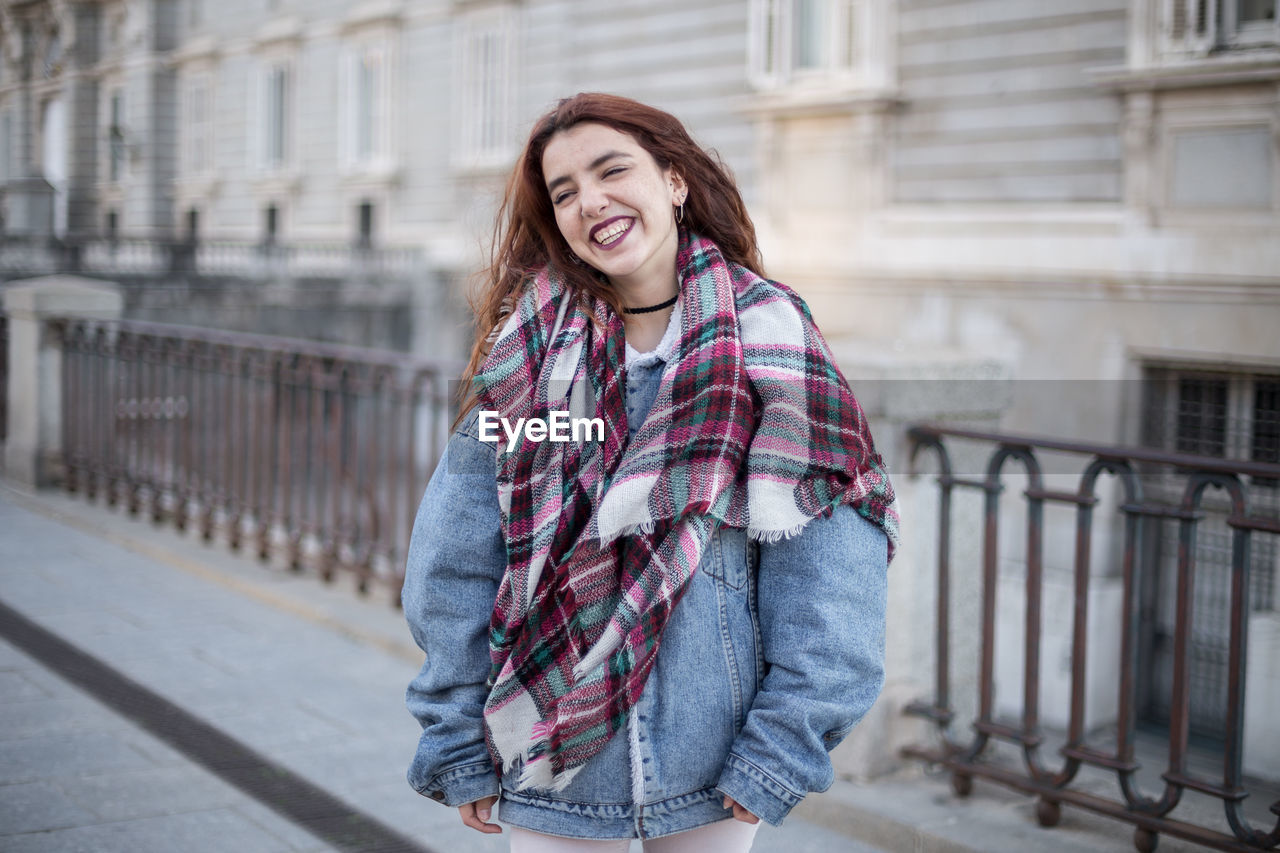 Smiling woman in warm clothes while standing in city during winter