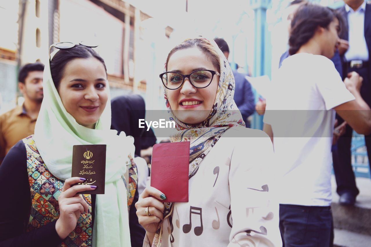 Portrait of smiling young women holding passports while standing outdoors