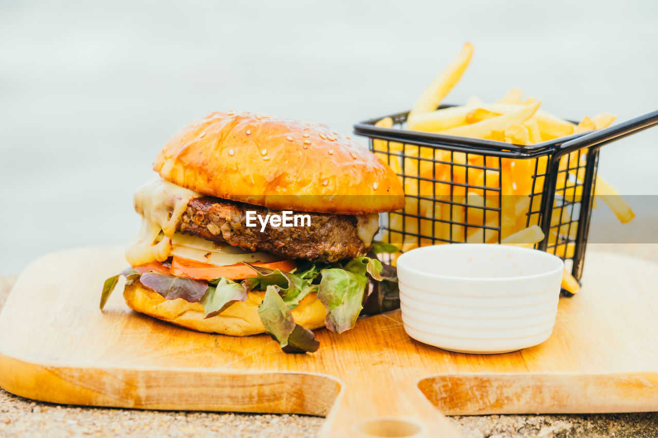Close-up of burger served on cutting board at beach