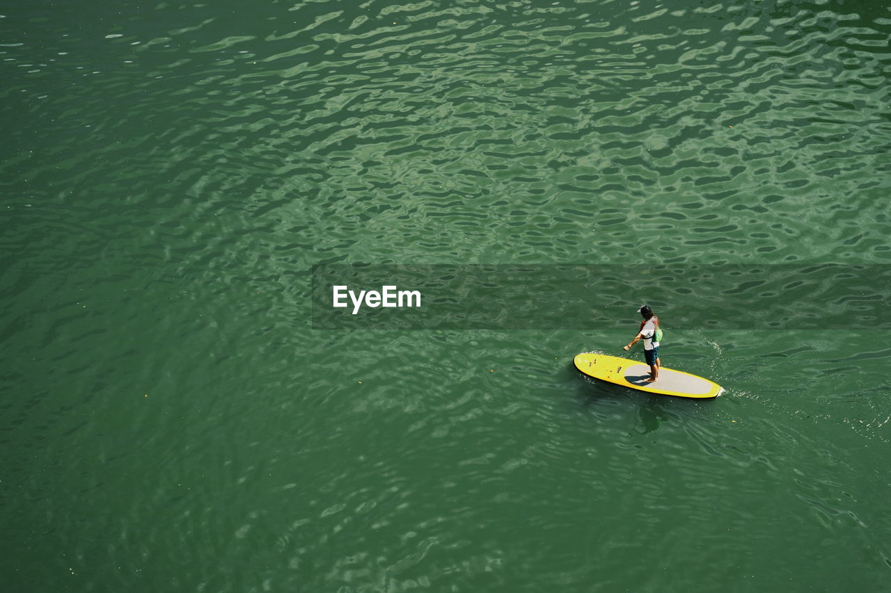 High angle view of man standing on surfboard in sea