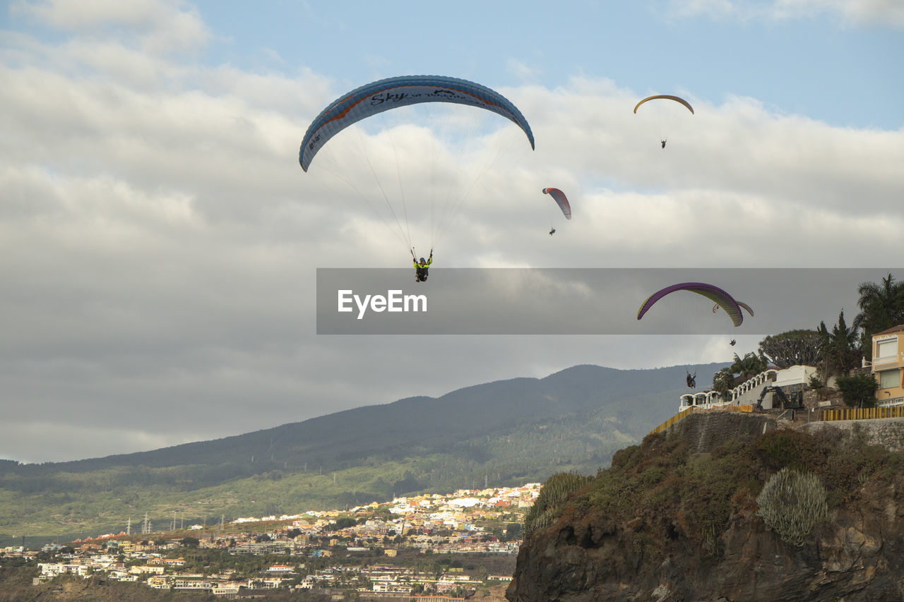 AERIAL VIEW OF PEOPLE PARAGLIDING AGAINST SKY