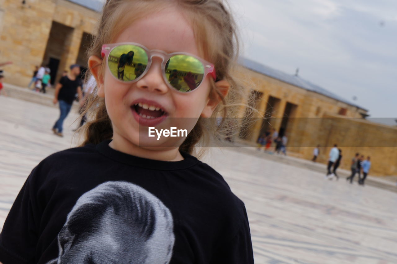 Close-up portrait of girl wearing sunglasses while standing against historic building