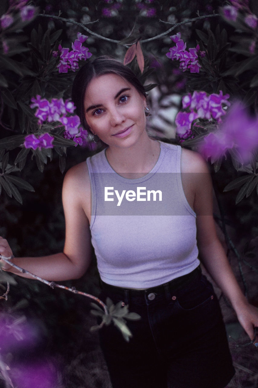 Portrait of young woman standing in front of a purple tree