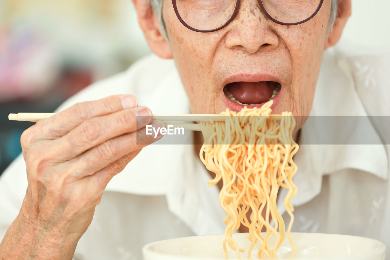 Senior woman eating noodles