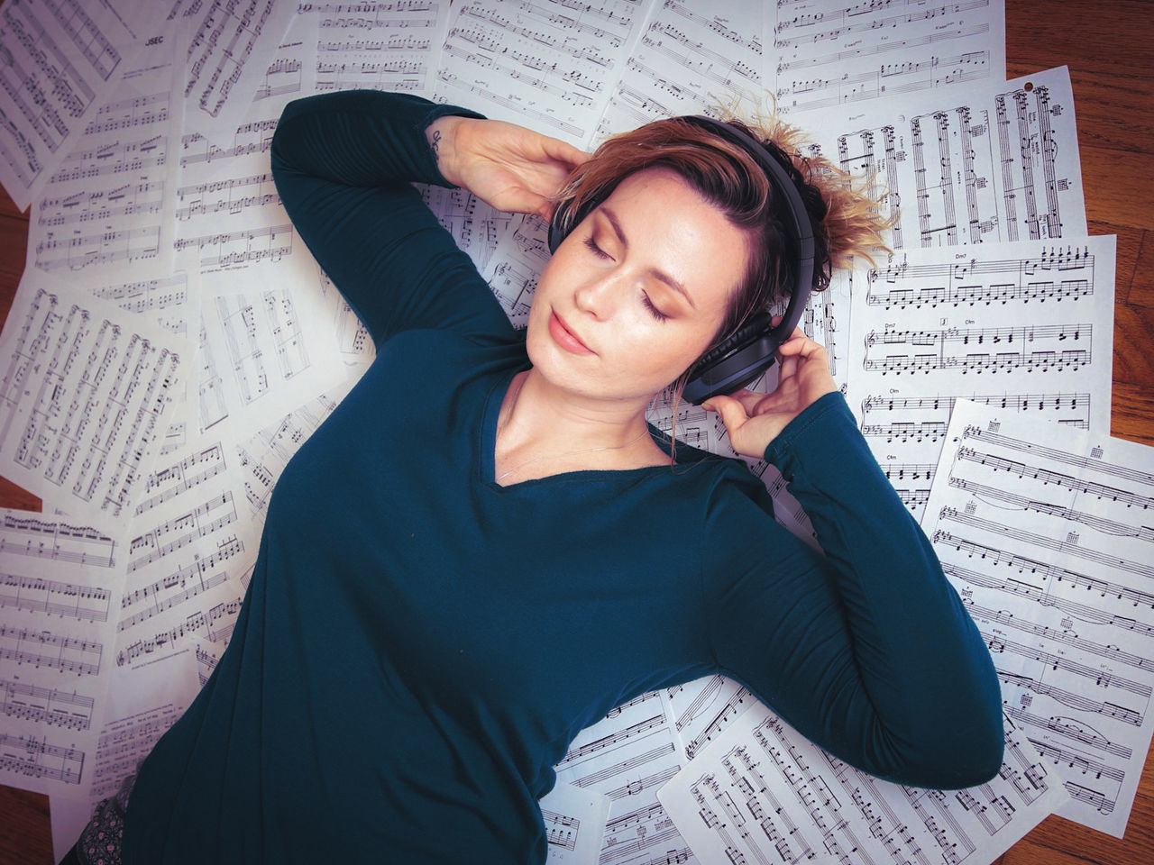 Woman listening music while lying on musical notes at home