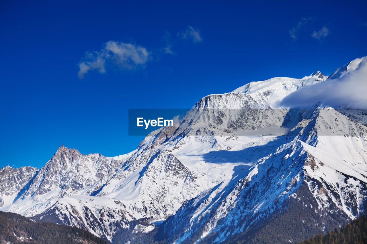 low angle view of snowcapped mountains against blue sky