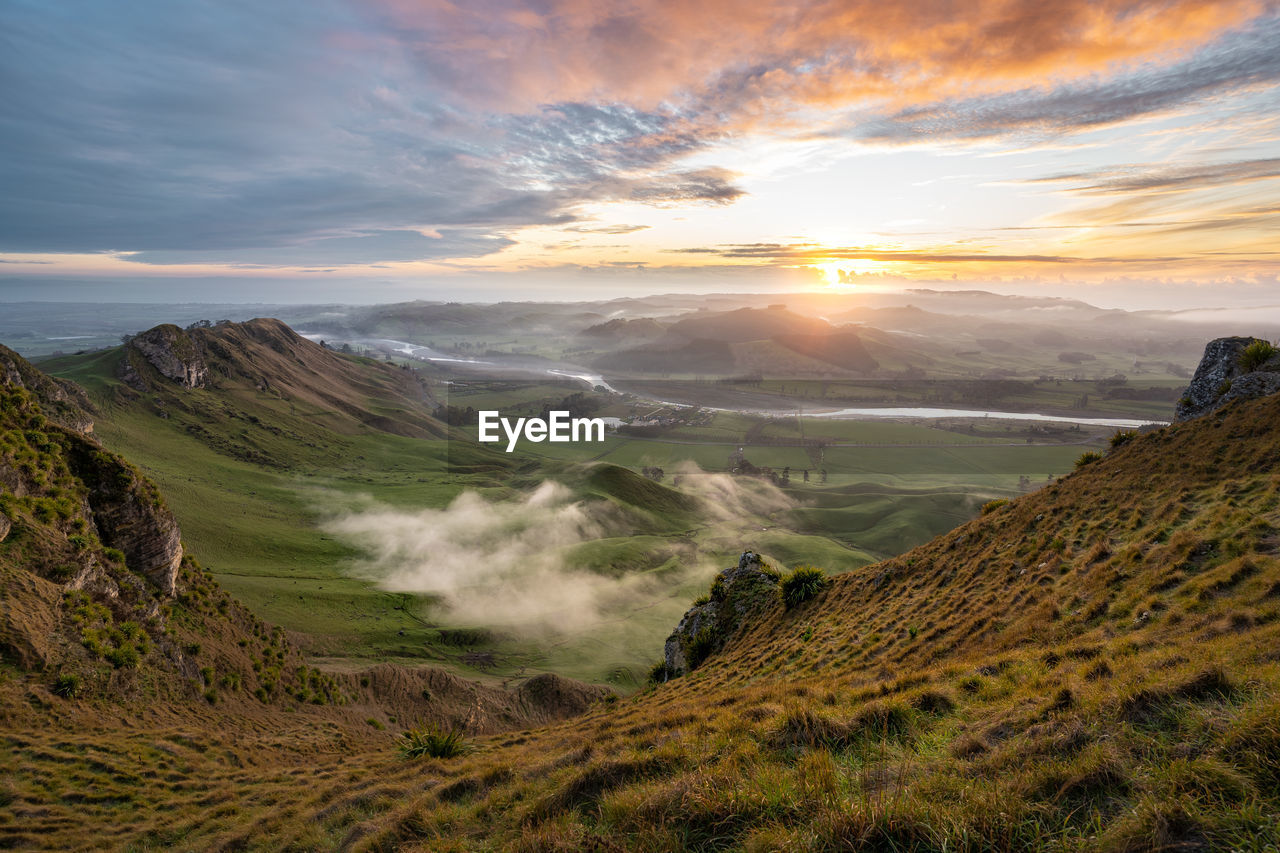 SCENIC VIEW OF LANDSCAPE AND MOUNTAINS AGAINST SKY DURING SUNSET