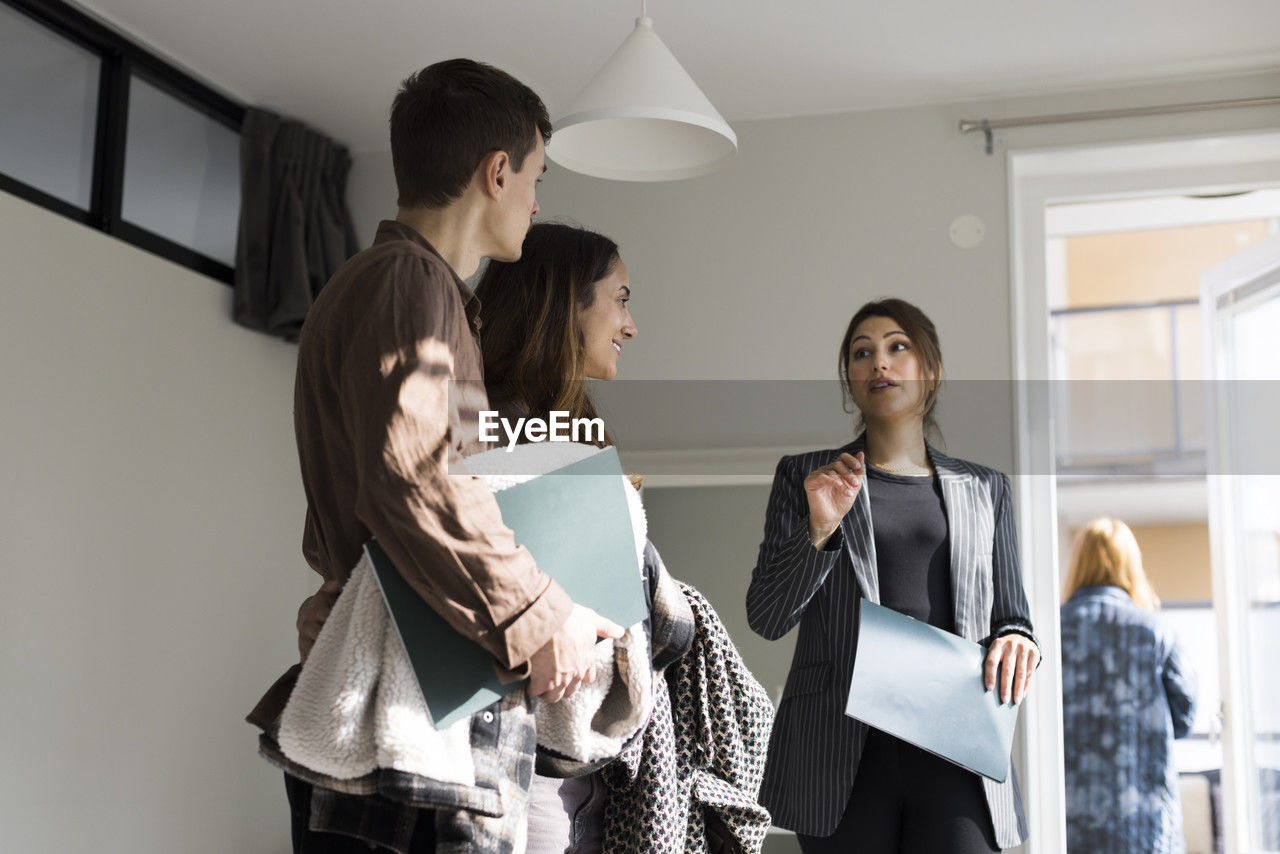 Low angle view of female real estate agent assisting clients during house visit