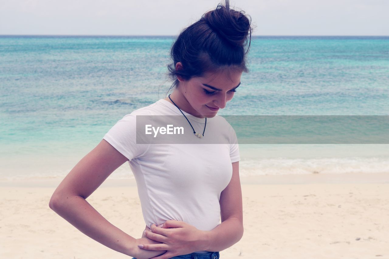 Teenage girl standing on beach against sea