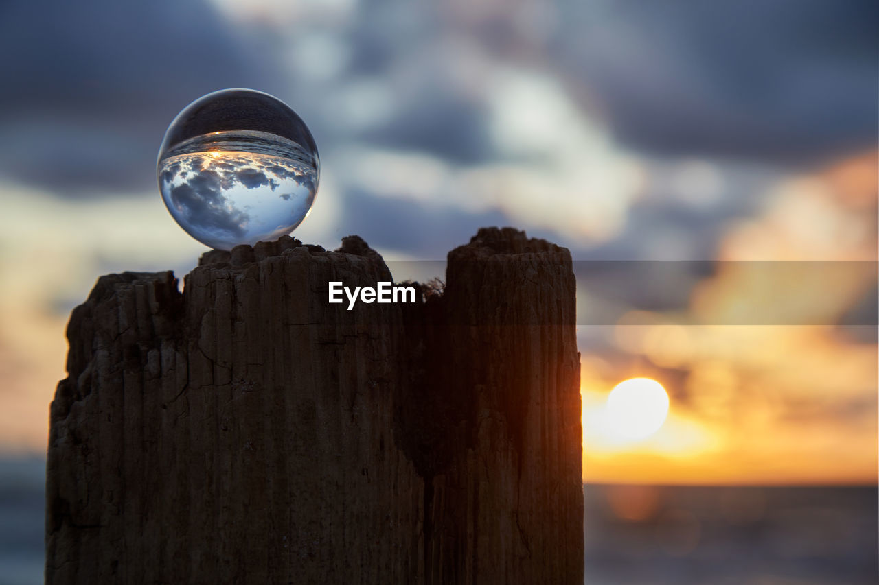 CLOSE-UP OF WOODEN POST ON ROCK AGAINST SKY