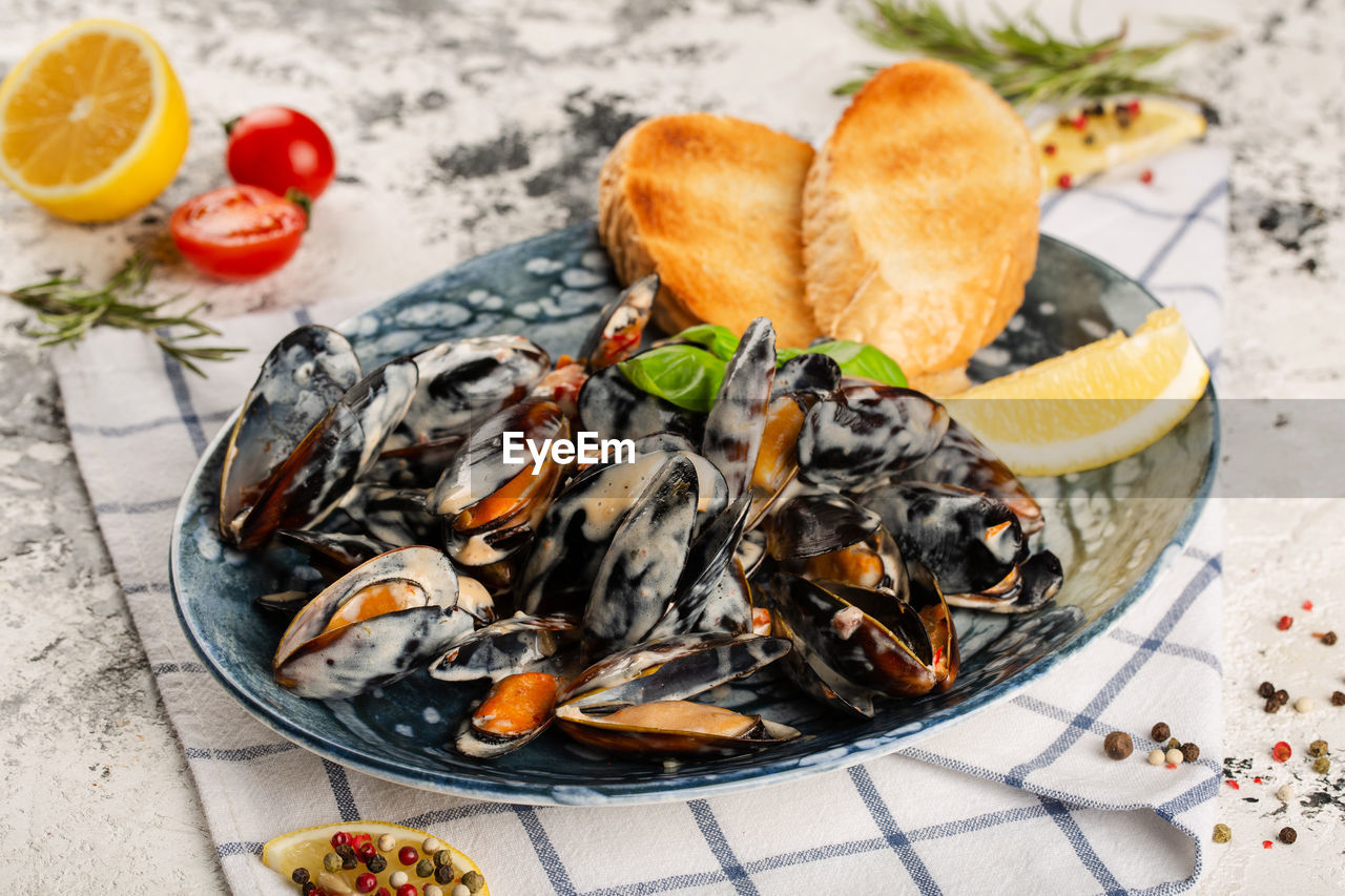 Mussels in a creamy sauce. served on a plate with bread toast.