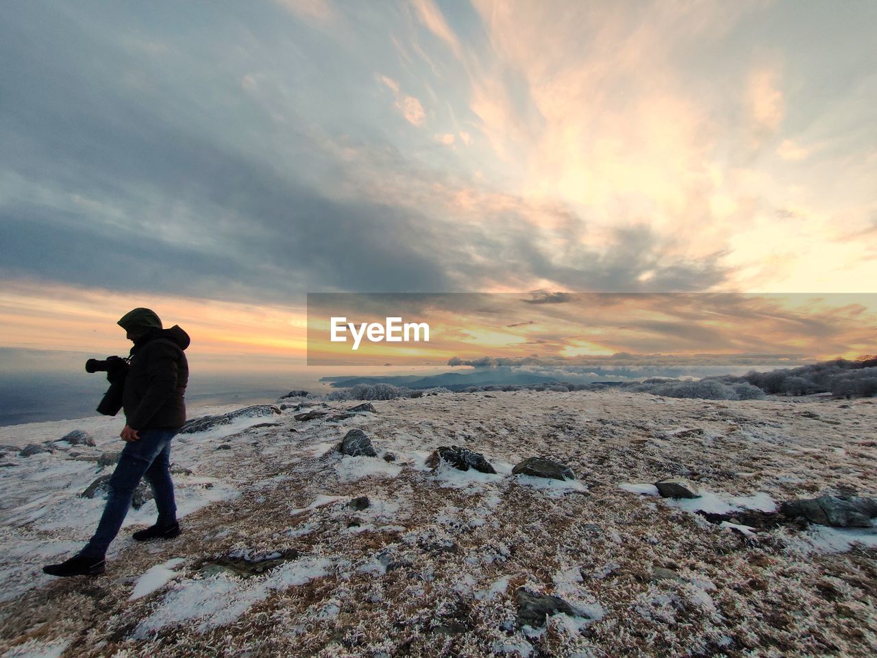 FULL LENGTH OF MAN STANDING ON SNOW DURING SUNSET