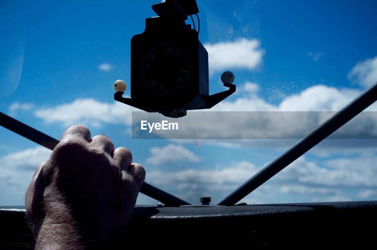 Cropped hand of man in air vehicle against sky