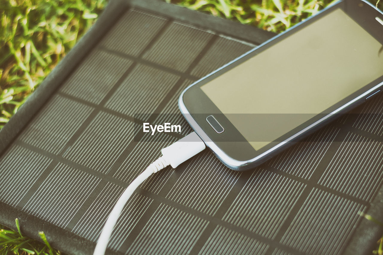 Close-up of mobile phone and solar charger