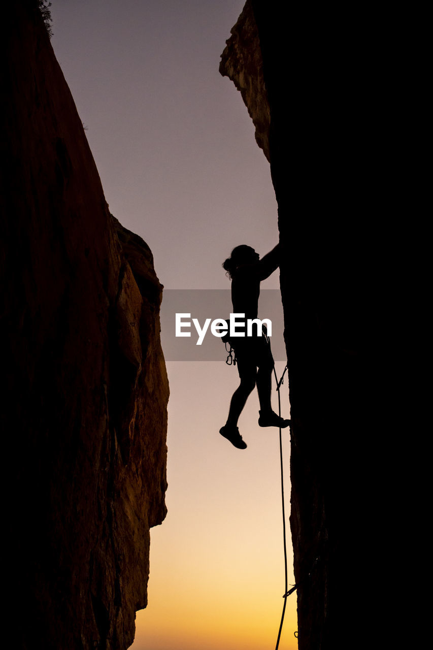 Beautiful view to silhouette of man climbing during sunset