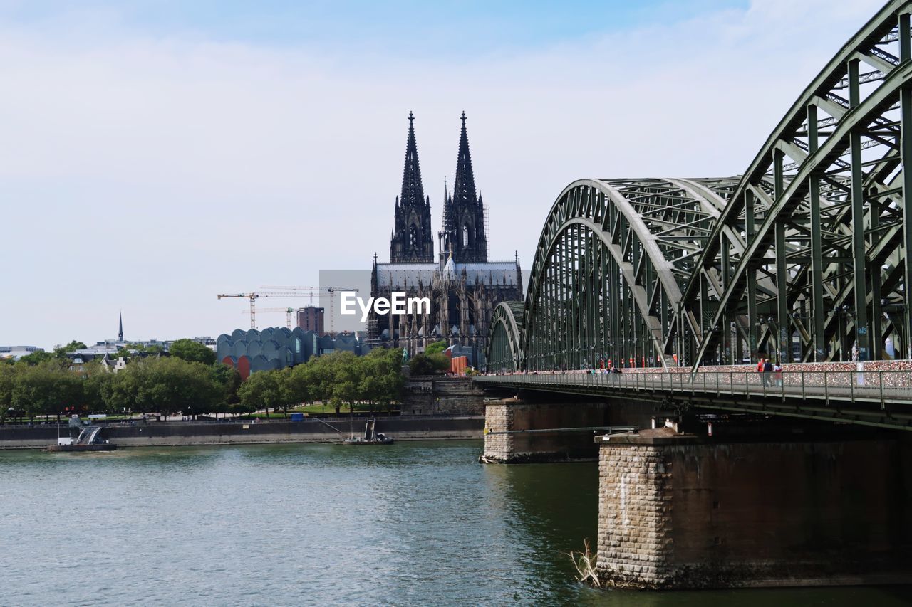 Bridge over river by buildings against sky