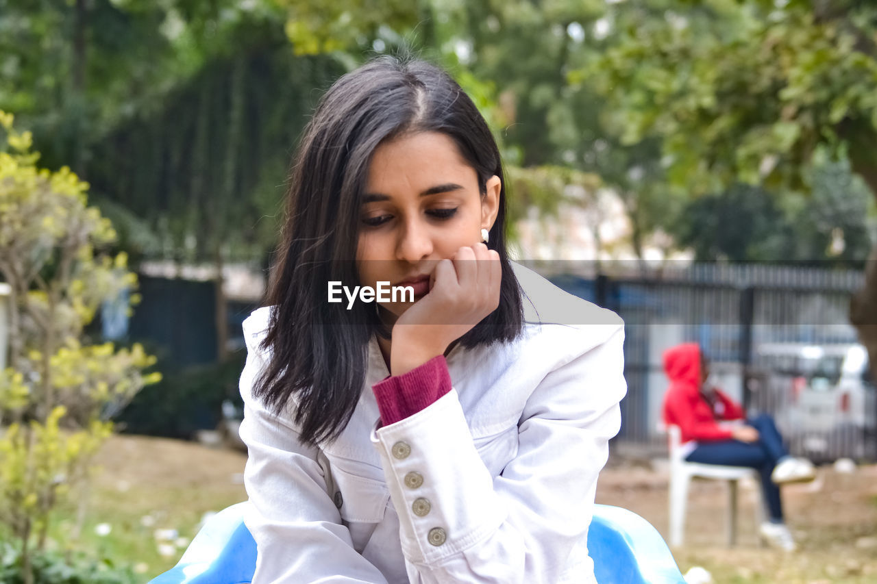 Thoughtful young woman sitting outdoors