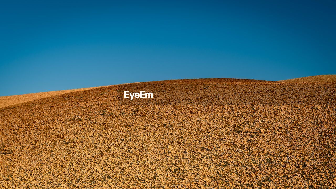 Scenic view of desert against clear blue sky