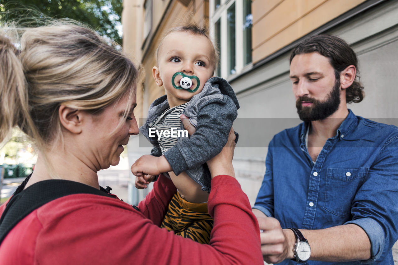 Mid adult parents with baby boy outside house