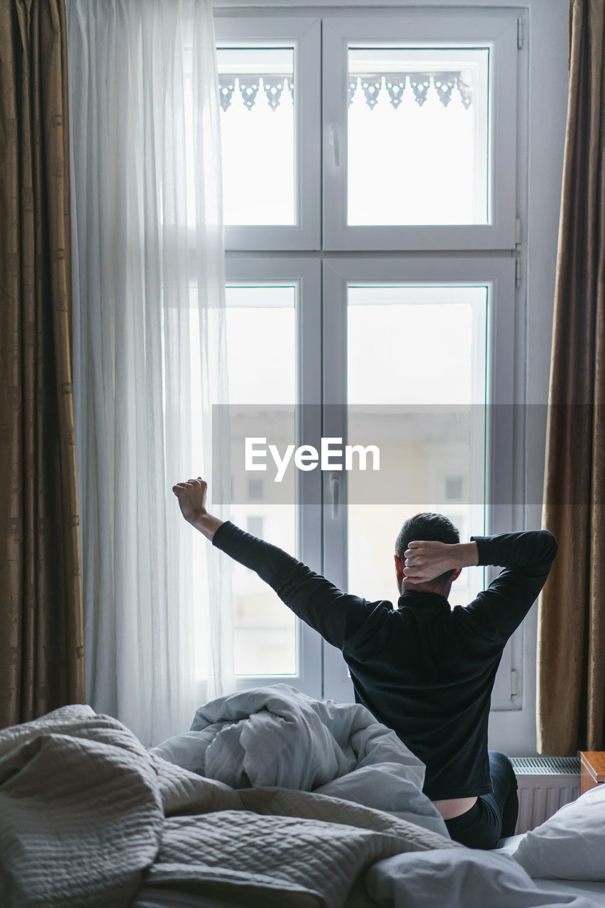 Young man sitting on bed at home