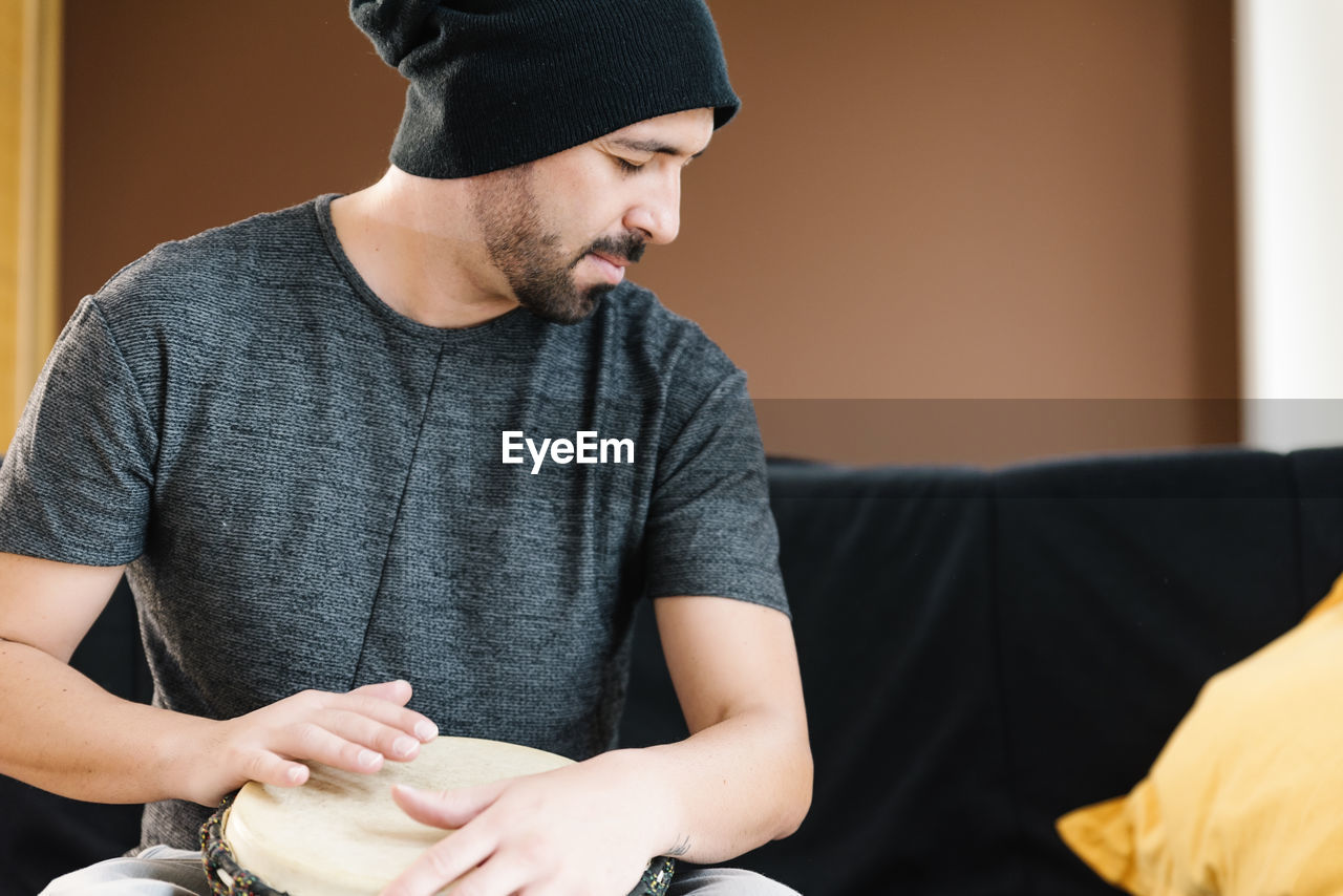 Man playing drum while sitting on sofa