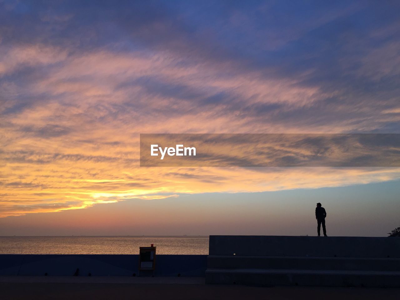 Silhouette man standing at beach against sky during sunset