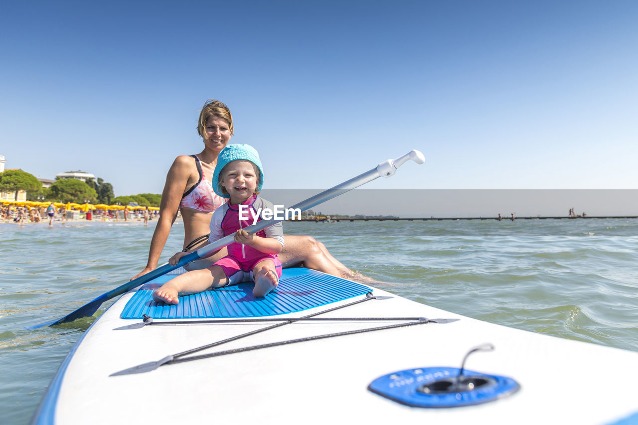 Happy mother and girl on paddleboard