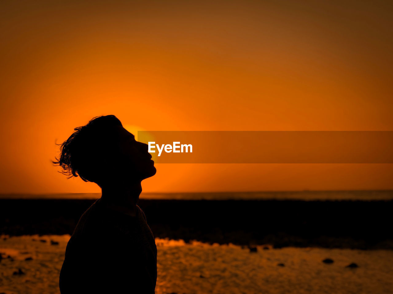 Silhouette man standing on beach against sky