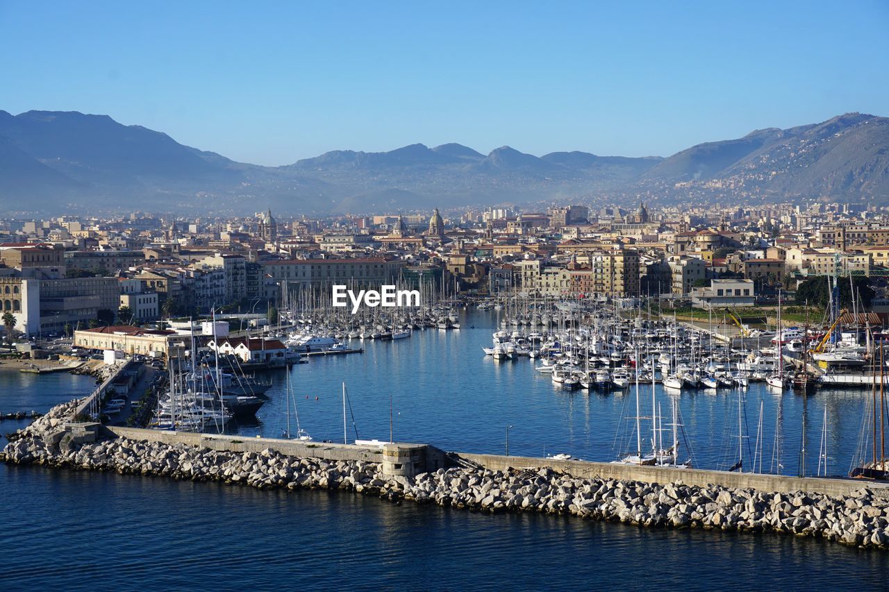 Sailboats in city against clear sky