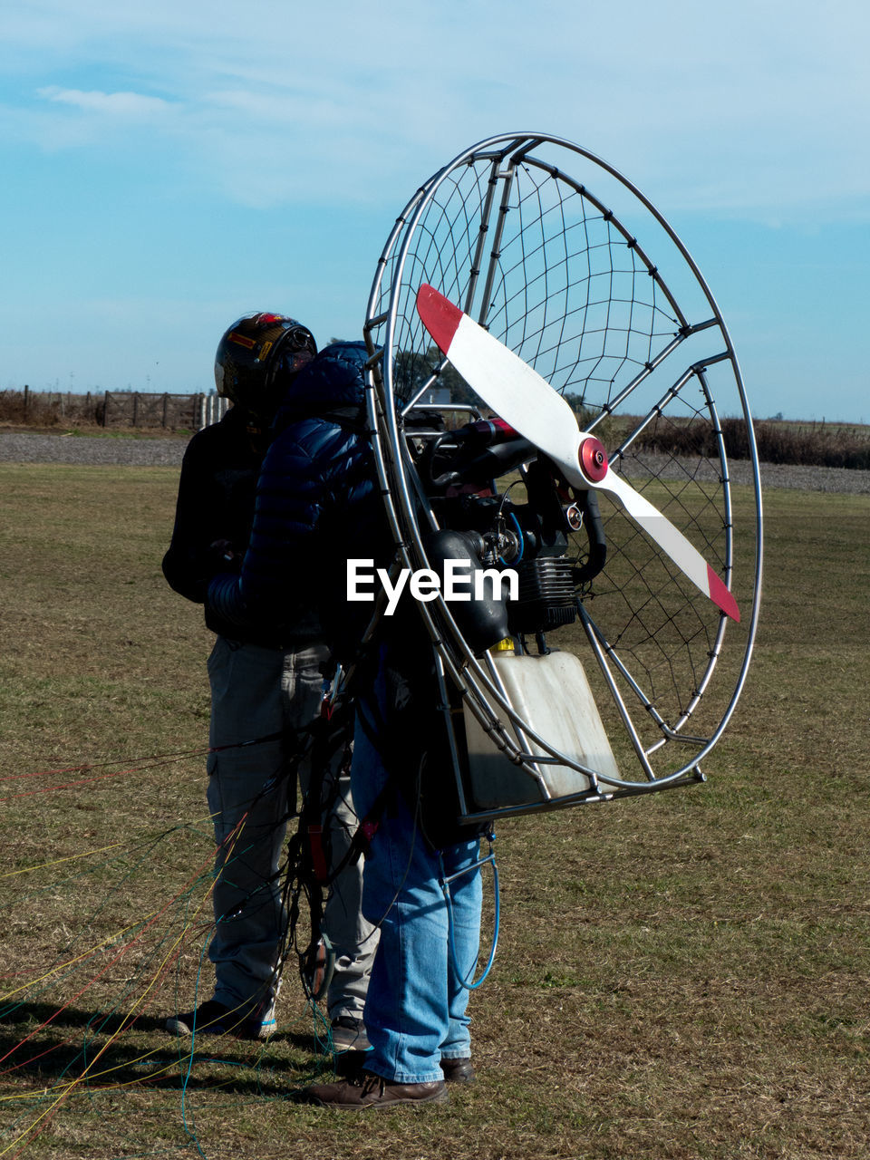 People with electric motor preparing for paragliding on land