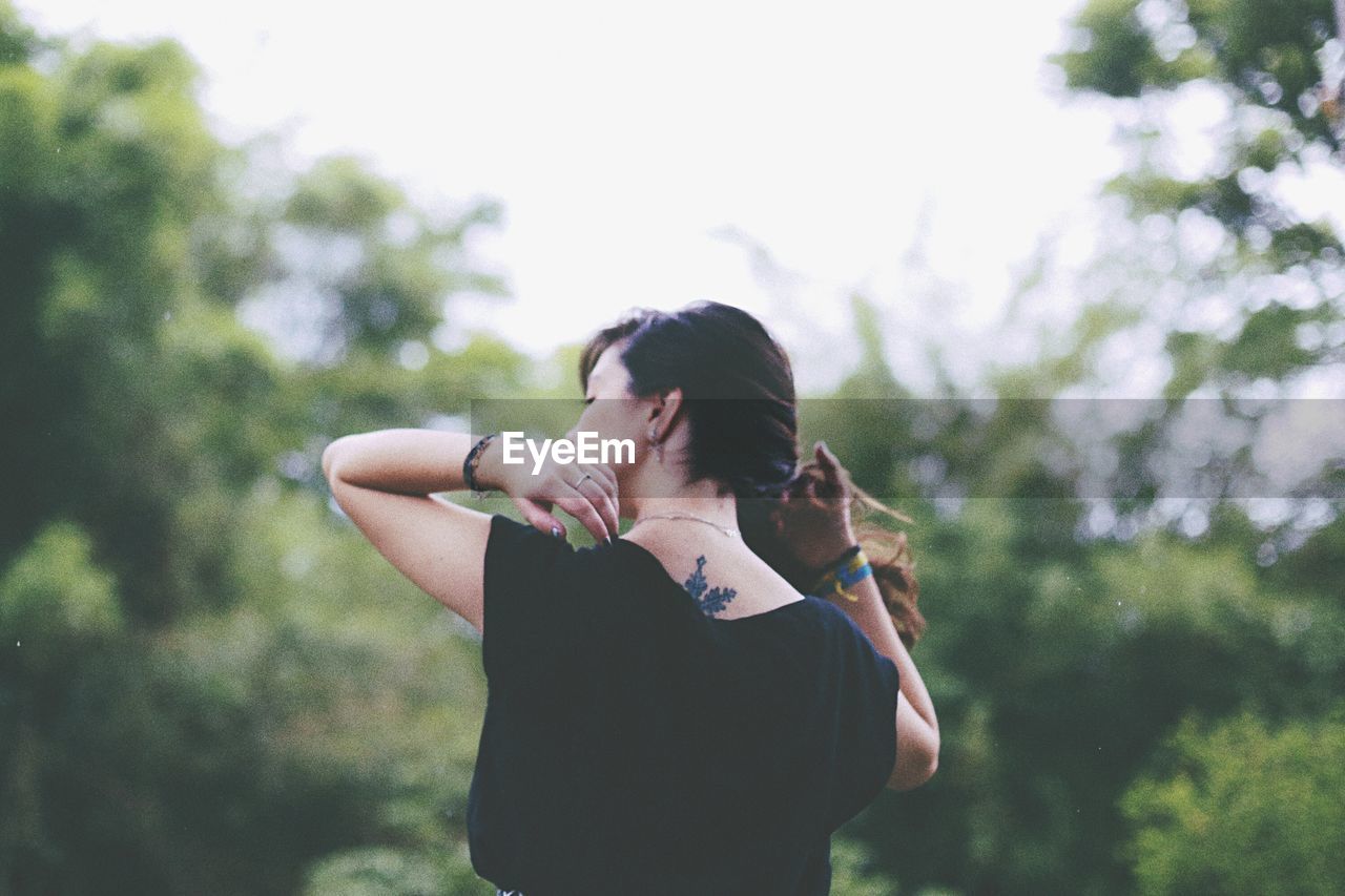 Rear view of woman with hand in hair standing on field