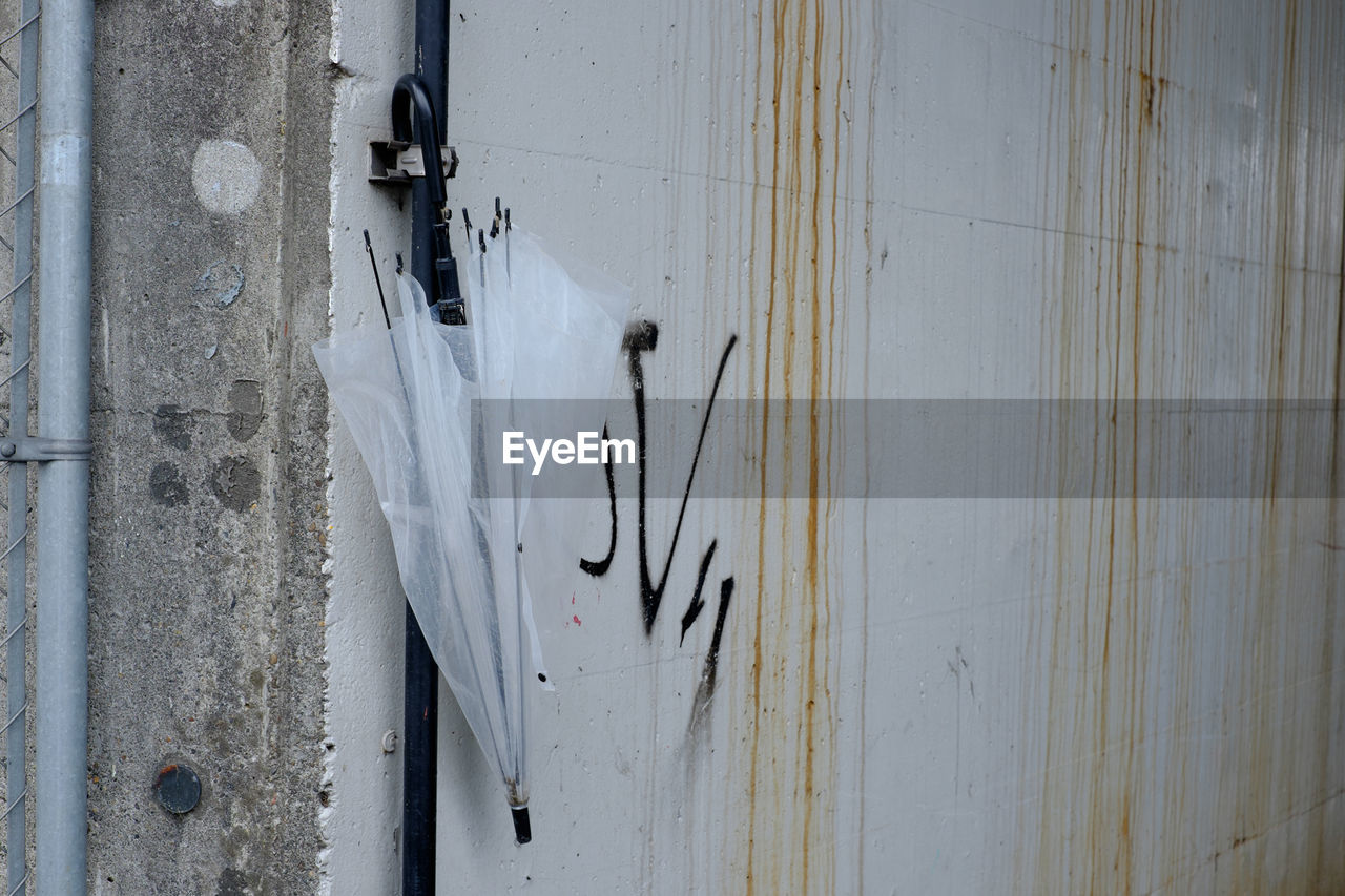 Umbrella hanging on wall by pipeline