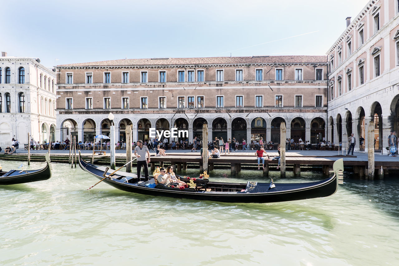 PEOPLE IN BOAT ON CANAL AGAINST BUILDINGS