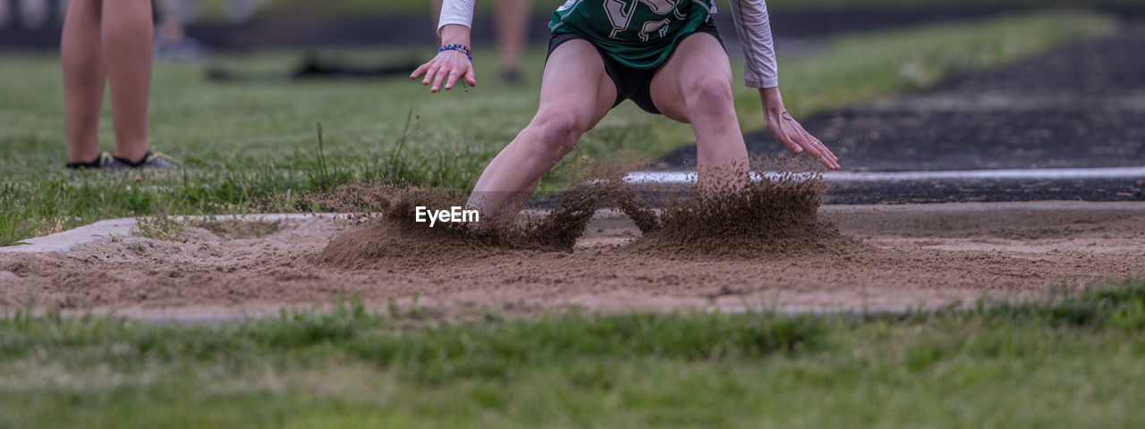 Full frame close-up view of a long jumper landing in the sand pit during a track meet