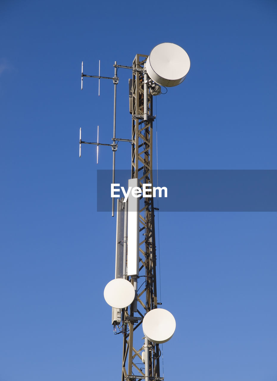 LOW ANGLE VIEW OF COMMUNICATIONS TOWER AGAINST BLUE SKY