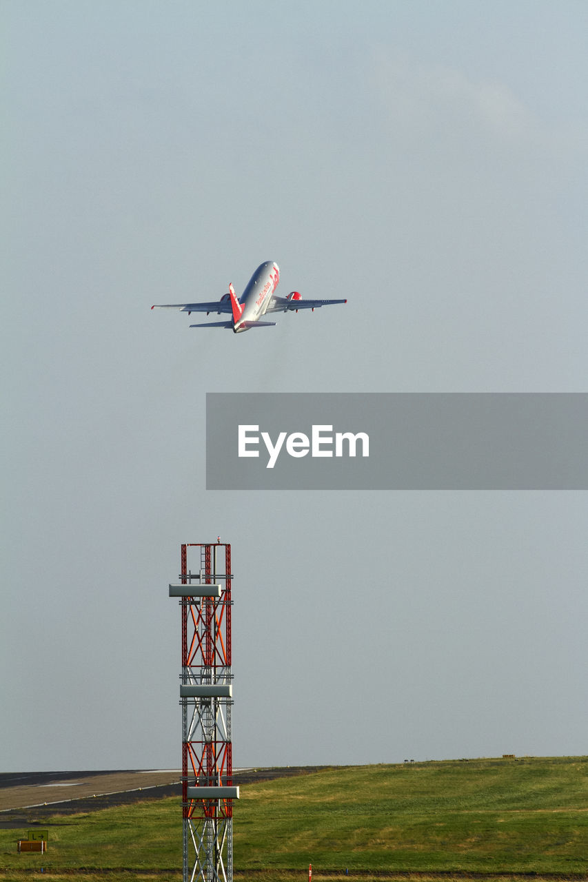 LOW ANGLE VIEW OF AIRPLANE FLYING OVER LAND