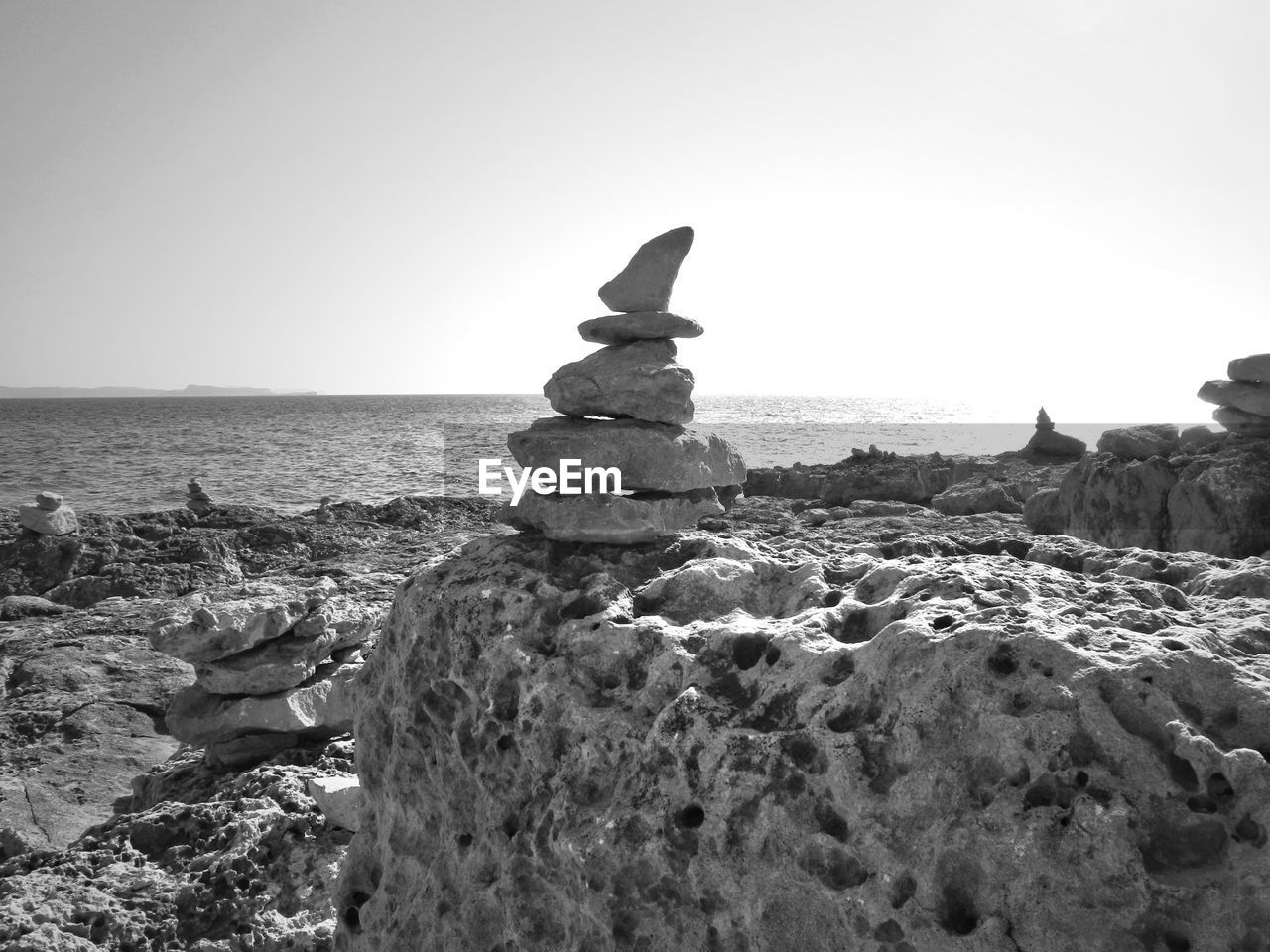 Sea in front of rock stack against clear sky on sunny day